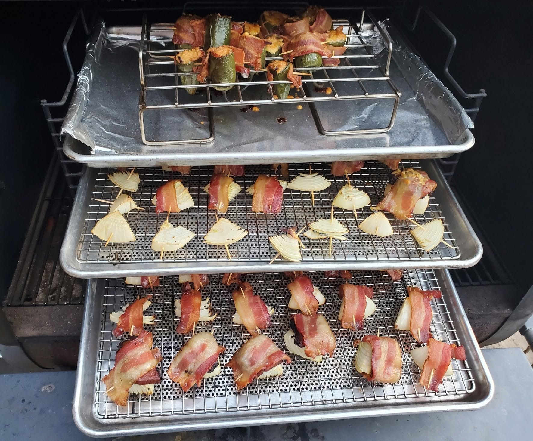 Bacon-wrapped jalapeño poppers smoking on stacked Bull Rack trays
