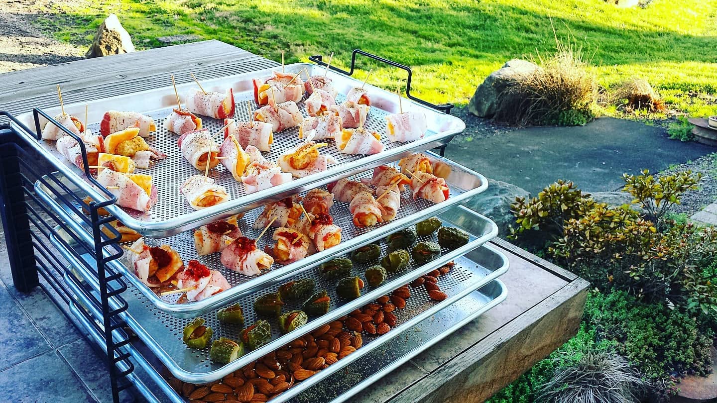 A loaded four-tier Bull Rack of bacon-wrapped bites, outdoors in golden light